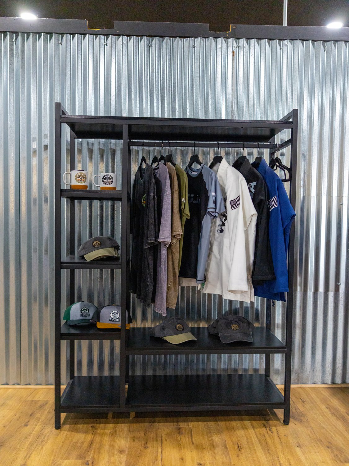 Pro shop rack with rash guards, shirts, hats, and academy mugs
